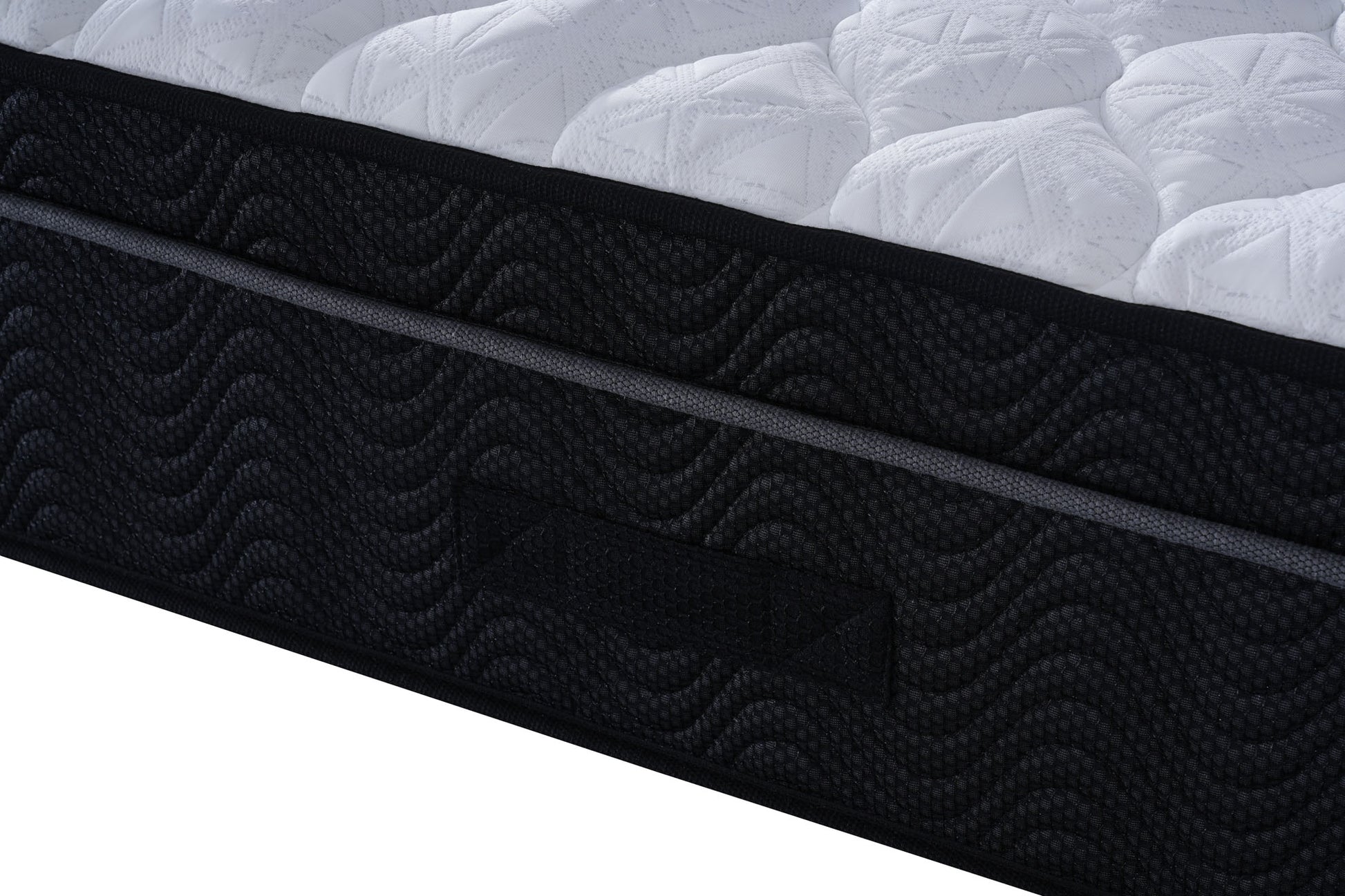 Close-up of a black mattress with textured surface and white bedding in the background