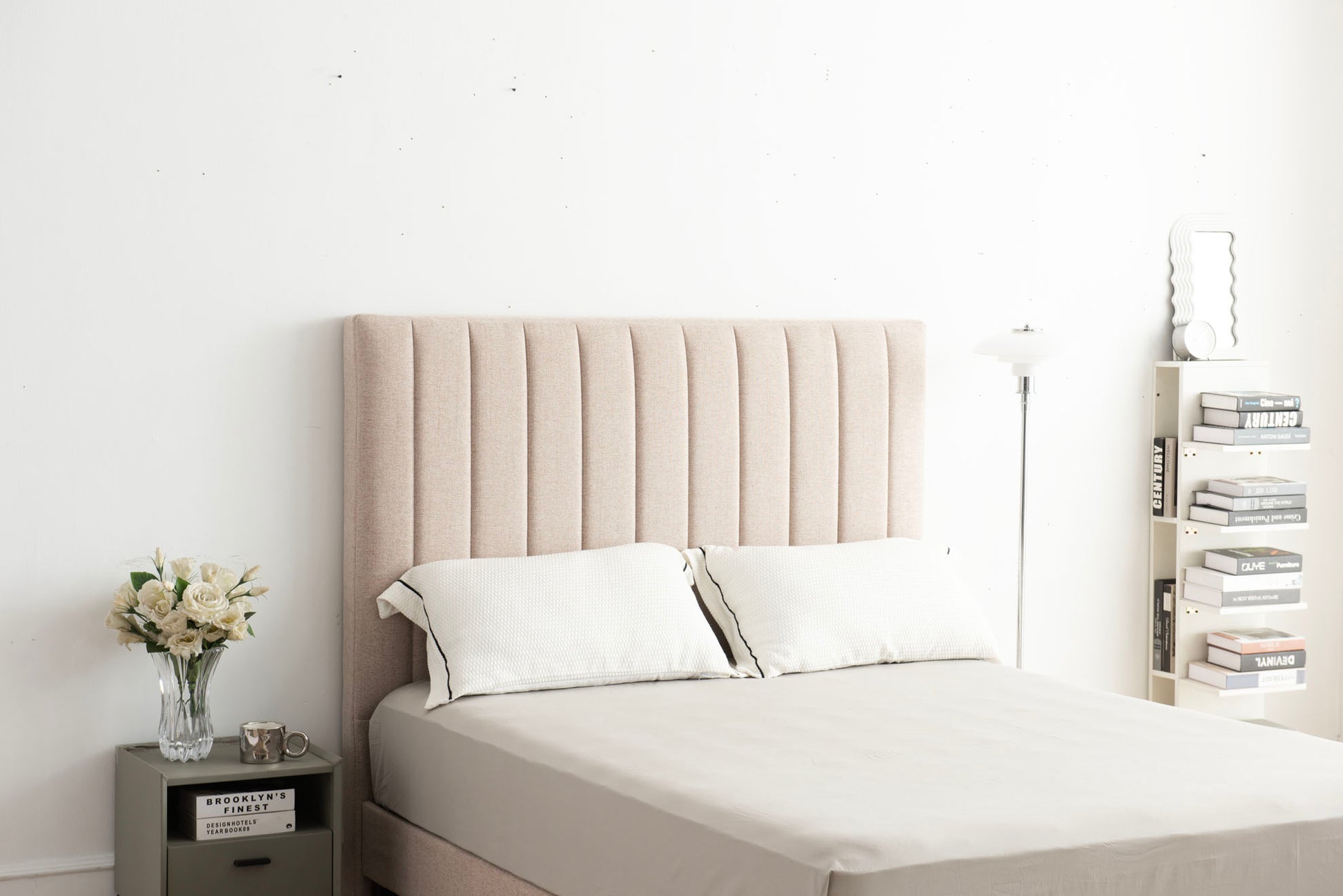 Beige upholstered headboard with white bedding in a minimalistic bedroom setting.